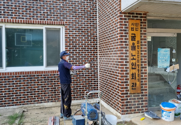 2021년 오른쪽 사회공헌활동 사진, 한 남자가 건물 벽을 보고 서서 벽면 시공을 보수하고 있다.